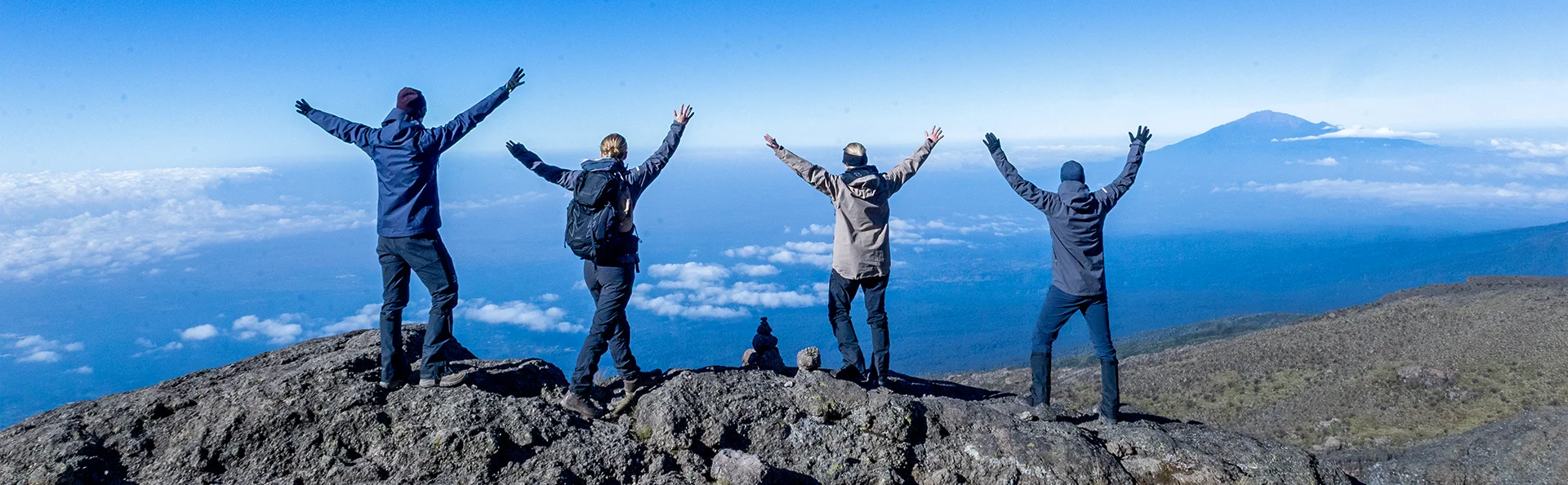 En gruppe står med hævede arme på toppen af Kilimanjaro