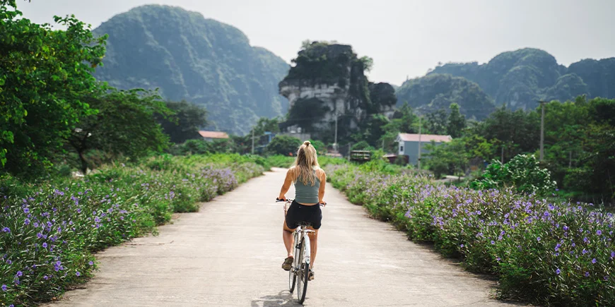 Kvinde cykler på en ensom vej i Ninh Binh i Vietnam