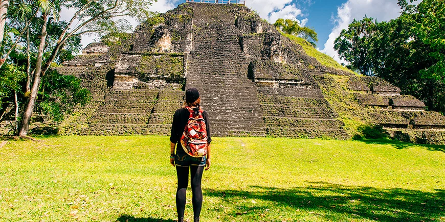 Kvinde står foran pyramide i Tikal Nationalpark