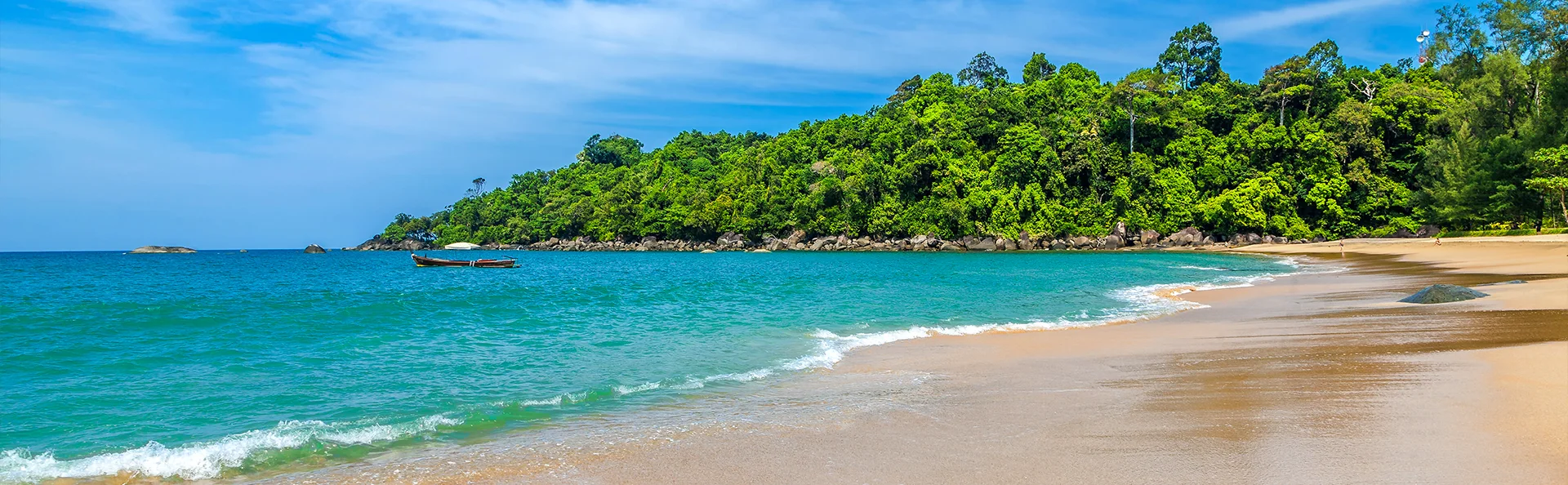 Tropisk strand i Thailand med turkis hav, blødt sand og grøn jungle i baggrunden.