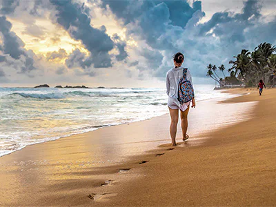 Kvinde går på stranden i Sri Lanka