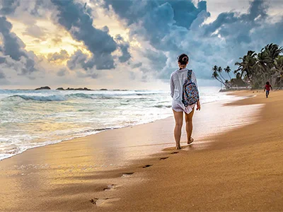 Kvinde går på stranden i Sri Lanka